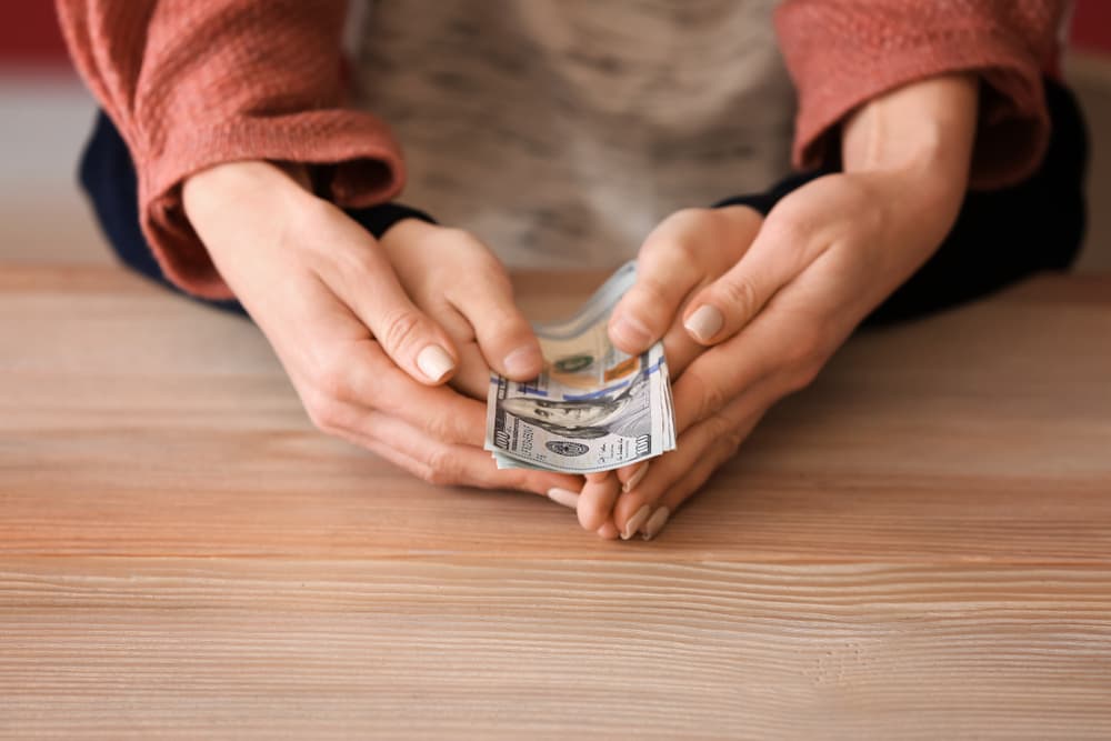 A woman and her son are sitting at a wooden table, holding dollar banknotes together. The scene symbolizes the concept of child support, highlighting their financial connection and care.






